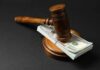 Trump’s $1.8B Slush Fund Slammed By Judge Judge’s gavel resting on a stack of US hundred-dollar bills