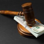 Trump’s $1.8B Slush Fund Slammed By Judge Judge’s gavel resting on a stack of US hundred-dollar bills
