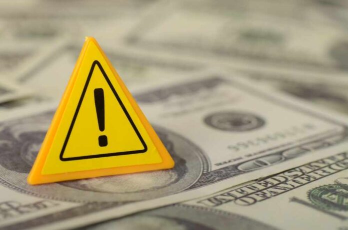 The,Image,Depicts,A,Cautionary,Message,About,The,Potential,Dangers A yellow warning sign placed on a pile of dollar bills