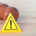 Yellow warning triangle with exclamation mark beside a wooden gavel
