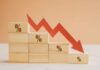 Savings Freefall Signals Quiet Crisis Wooden blocks with percentage symbols and a downward arrow indicating decline