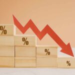 Savings Freefall Signals Quiet Crisis Wooden blocks with percentage symbols and a downward arrow indicating decline