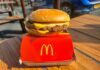 McDonald’s Plays Patriotism With A Fan Favorite A cheeseburger from McDonald's placed on a red box on a wooden table