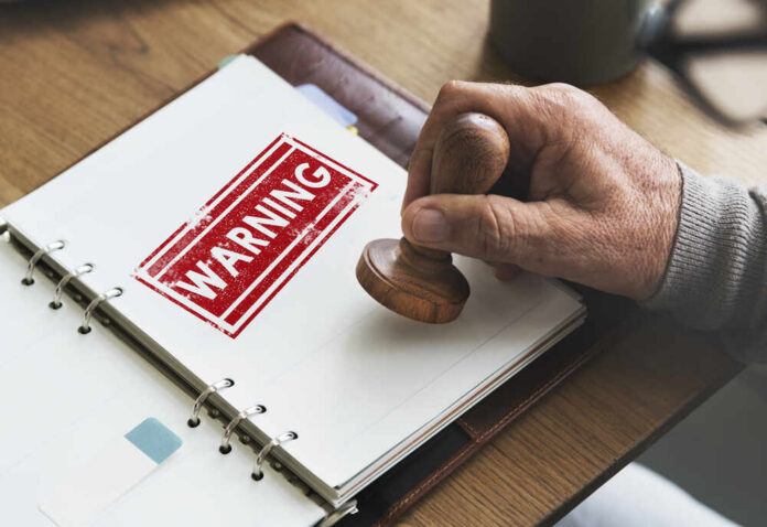 Caution,Denied,Pending,Rejected,Secret,Warning,Concept A hand applying a warning stamp on a document