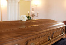 Beloved Actor Gone — Hollywood Reeling A wooden casket with a white rose placed on top in a solemn setting