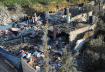 People inspecting rubble and debris of destroyed buildings.