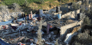 People inspecting rubble and debris of destroyed buildings.