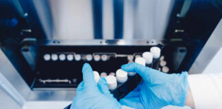 Person in blue gloves handling test tubes in a laboratory