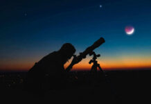 Cosmic Beacons Shatter Early-Universe Timeline Silhouette of person using telescope against colorful twilight sky.