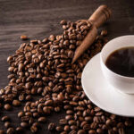 Coffee Shock: AHA Backs Five Cups A cup of hot coffee next to spilled coffee beans and a wooden scoop