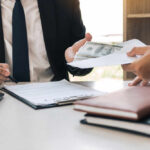 Two individuals engaged in a business transaction involving money and documents