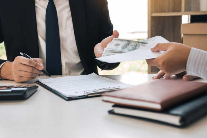 Entrepreneurs,Are,Signing,A,Contract,About,Business,Under,Fraud,While Two individuals engaged in a business transaction involving money and documents