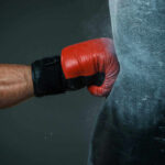 Boxers gloved hand punching a heavy bag.