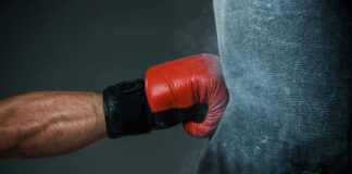 Boxers gloved hand punching a heavy bag.