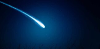 A bright comet streaking across a dark night sky filled with stars