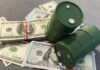 UPDATE: Oil Slide Nears Pre-War Lows Two green barrels placed on a pile of hundred dollar bills