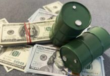 UPDATE: Oil Slide Nears Pre-War Lows Two green barrels placed on a pile of hundred dollar bills