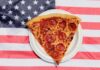 Pizza Giant Bleeds Cash, Slams Doors Pepperoni pizza slice on a paper plate over an American flag