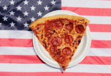 Pizza Giant Bleeds Cash, Slams Doors Pepperoni pizza slice on a paper plate over an American flag