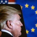 Trump Threatens Full Europe Pullout Profile view of a man displayed on a smartphone in front of American and European flags