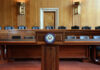 Unlikely Duo Demands Millions — Why Now? Empty Senate chamber with a wooden podium and chairs
