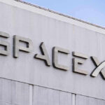 Gravity Targets SpaceX — Lunar Smash Imminent SpaceX building logo against blue sky.