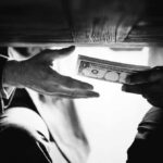 Bank Blacklist: Why 300 Trump Accounts Vanished? Hands passing money under a table, shrouded in mystery.