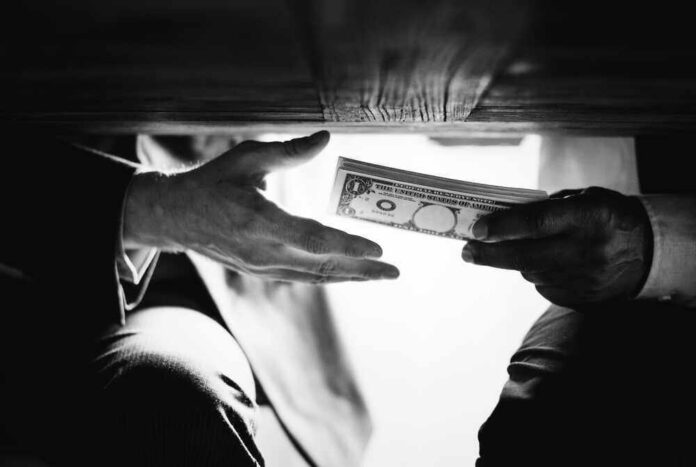Hands passing money under a table, shrouded in mystery.