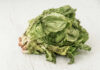 Taco Bell Lettuce Sparks Parasite Panic Wilted lettuce head on a white wooden surface