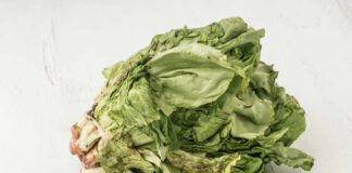 Wilted lettuce head on a white wooden surface