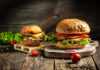 Burger Relief Or Heartland Hit? Gourmet burgers on rustic wooden boards with fresh toppings