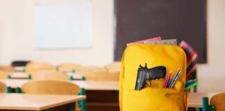 A yellow backpack with a gun partially visible in a classroom setting