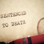 Close-up of a typewritten document stating 'SENTENCED TO DEATH'