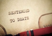 Close-up of a typewritten document stating 'SENTENCED TO DEATH'