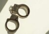A pair of metallic handcuffs resting on a light surface