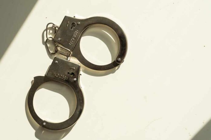 Handcuffs,Short,Chain,Black,Metal,On,White.,3d,Illustration A pair of metallic handcuffs resting on a light surface