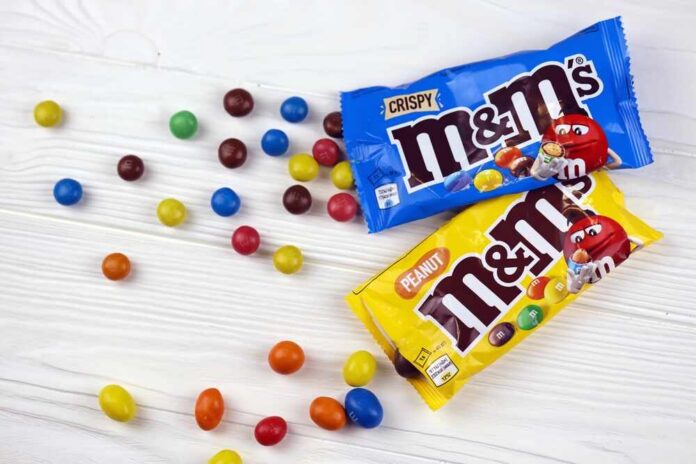 M&M's candy bags with scattered colorful candies on a white table