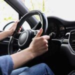 Hands gripping a steering wheel inside a car