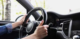 Hands gripping a steering wheel inside a car