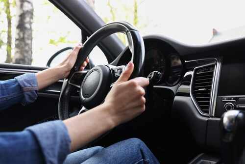 Hands gripping a steering wheel inside a car