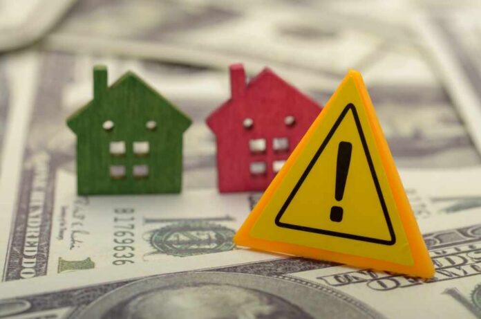 A,Warning,About,Potential,Financial,Risks,Or,Challenges,Associated,With Colorful house models and a warning sign on dollar bills