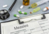 Medical supplies including a stethoscope, syringes, and medication related to measles