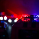 Police Tech Showdown: These Gloves Outlawed? Police car lights shining in the dark.