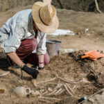 Amazing Discovery: Lost Monastery Found Under Soccer Field Archaeologist excavating skeletal remains at an archaeological site.