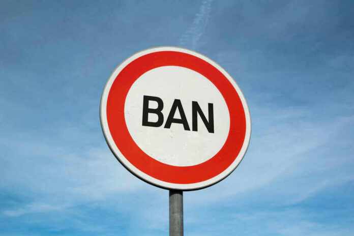 shutterstock_1759263689 Sign reading BAN against blue sky background