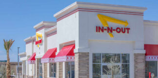 In-N-Out Burger sign with yellow arrow in city setting