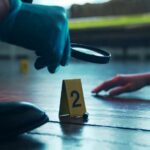 Killer’s Gambit: Judge On The Hot Seat A detective examining evidence at a crime scene with markers on the floor