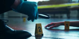 A detective examining evidence at a crime scene with markers on the floor