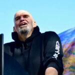 Dems Turn On Fetterman? John Fetterman speaking at podium.