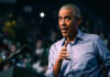 Obama DARES Dems To Do THIS?! Barack Obama in blue shirt speaking at podium with microphone.